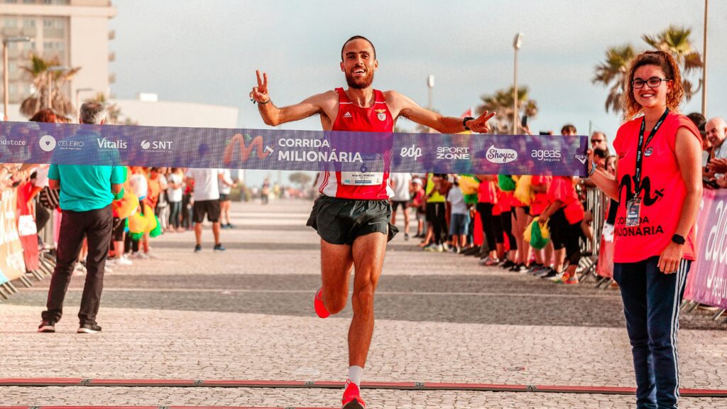 Male runner celebrates crossing the finish line in an outdoor marathon race.