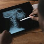 Doctor examining a spinal x-ray on a tablet using a stylus. Modern medical analysis.